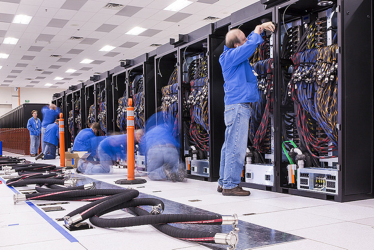 The Cray installation team is preparing a row of 12 cabinets (out of 60 total) for connection to the water cooling infrastructure at Los Alamos National Laboratory. (Photo courtesy LANL)